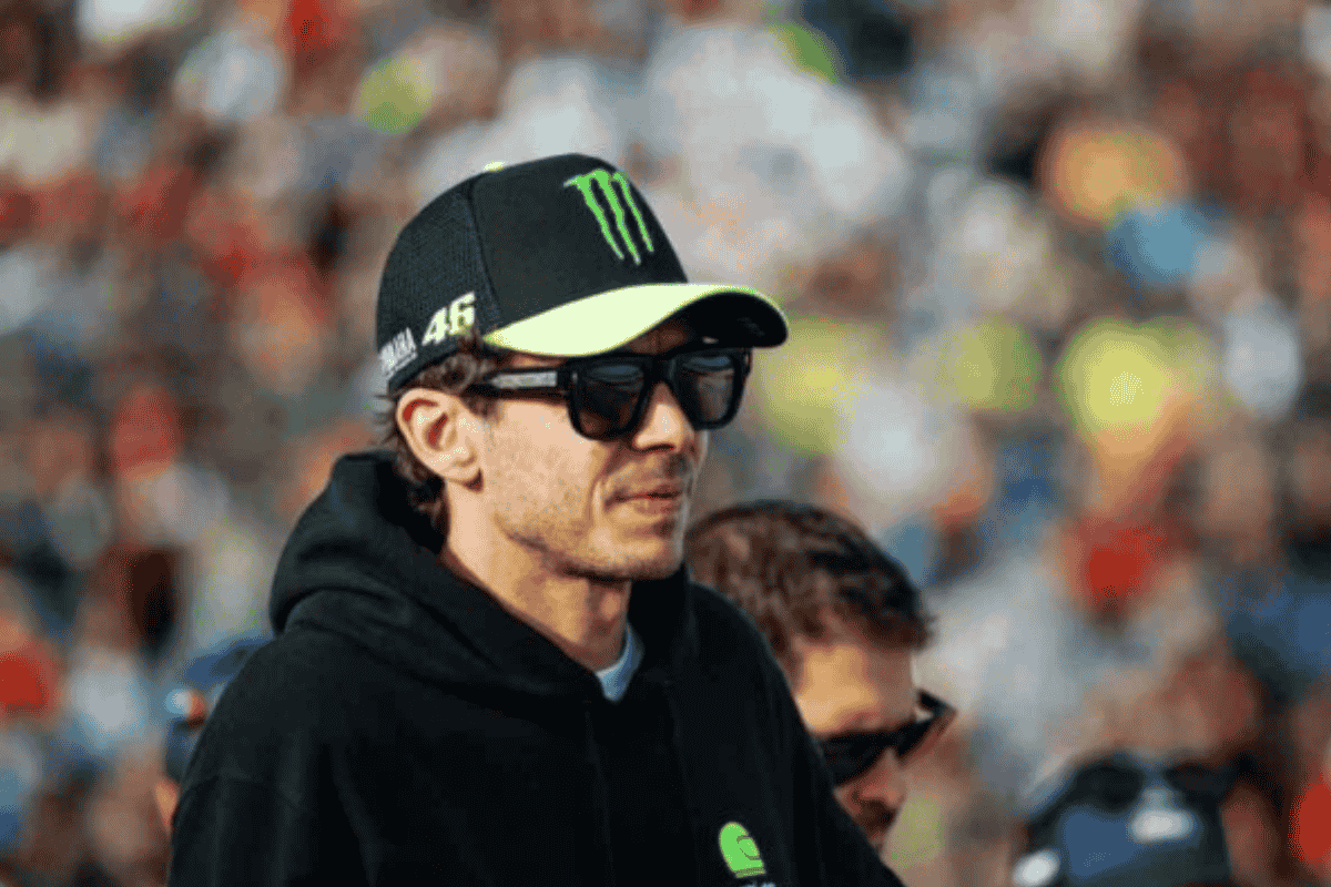 Valentino Rossi indossa una felpa nera, occhiali da sole e un cappello nero con logo Monster e visiera gialla